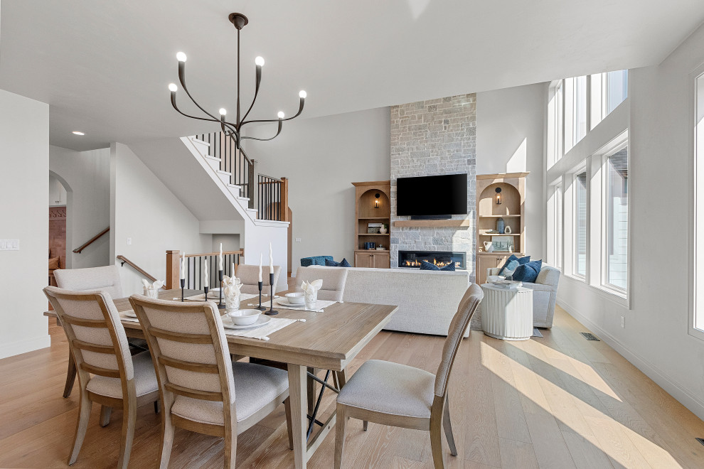 Large transitional medium tone wood floor and brown floor great room photo with white walls, a standard fireplace and a stone fireplace