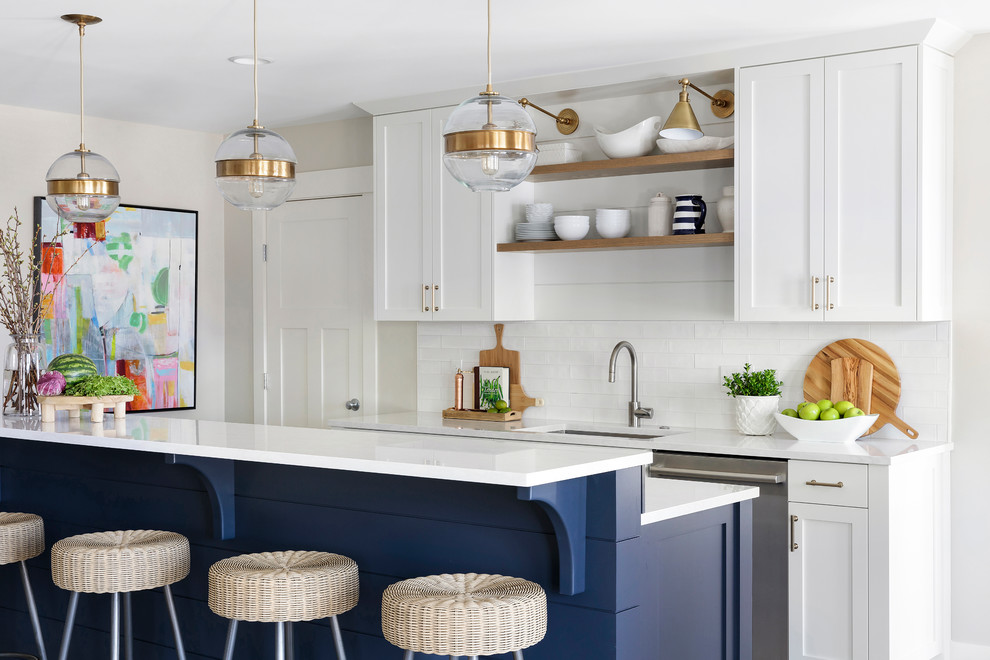 Inspiration for a beach style galley open plan kitchen in Minneapolis with an undermount sink, shaker cabinets, white cabinets, white splashback, subway tile splashback, stainless steel appliances, with island, white benchtop, quartz benchtops and ceramic floors.