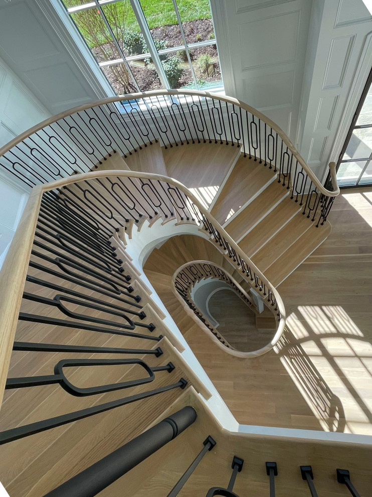 Réalisation d'un très grand escalier courbe tradition avec des marches en bois, des contremarches en bois, un garde-corps en matériaux mixtes et boiseries.