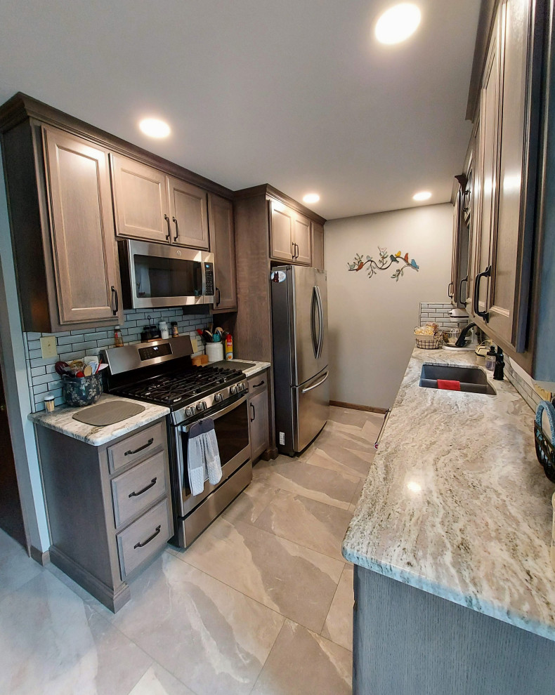 Photo of a mid-sized country u-shaped eat-in kitchen in Other with a drop-in sink, dark wood cabinets, granite benchtops, white splashback, subway tile splashback, stainless steel appliances, ceramic floors, grey floor and beige benchtop.