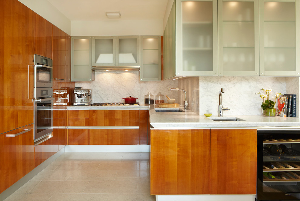 This is an example of a large modern separate kitchen in New York with an undermount sink, flat-panel cabinets, medium wood cabinets, marble benchtops, white splashback, stone slab splashback, stainless steel appliances and beige floor.
