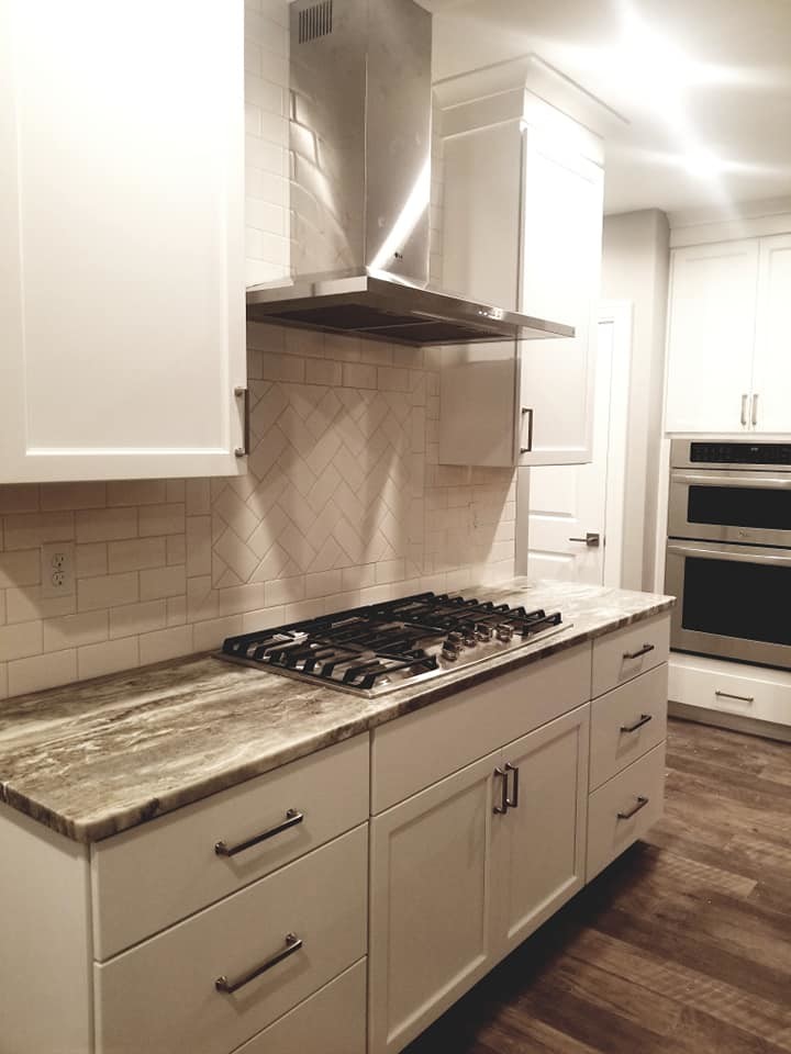 Kitchen - transitional brown floor kitchen idea with an undermount sink, flat-panel cabinets, white cabinets, quartzite countertops, white backsplash, subway tile backsplash, stainless steel appliances and an island