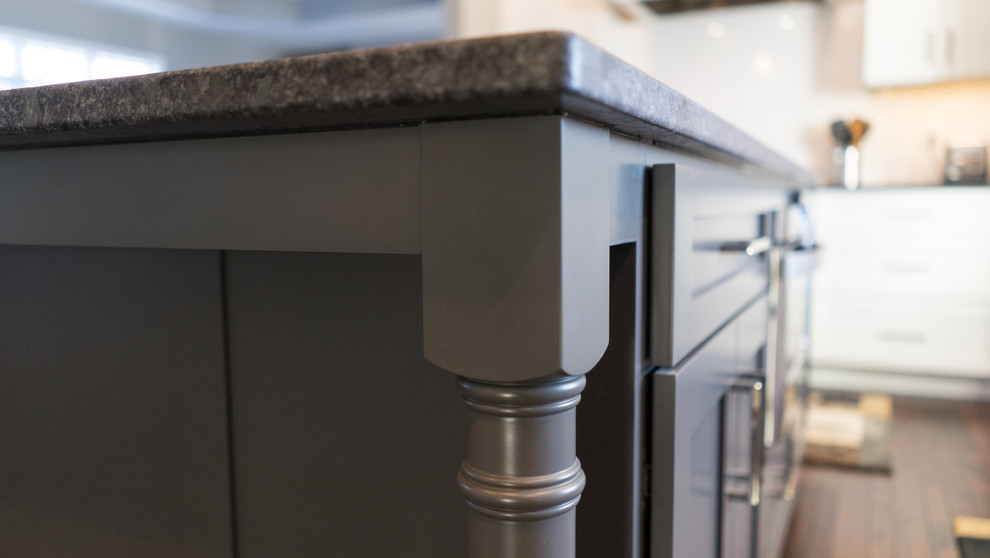 Eat-in kitchen - large transitional u-shaped eat-in kitchen idea with a farmhouse sink, flat-panel cabinets, white cabinets, granite countertops, white backsplash, ceramic backsplash, stainless steel appliances and an island