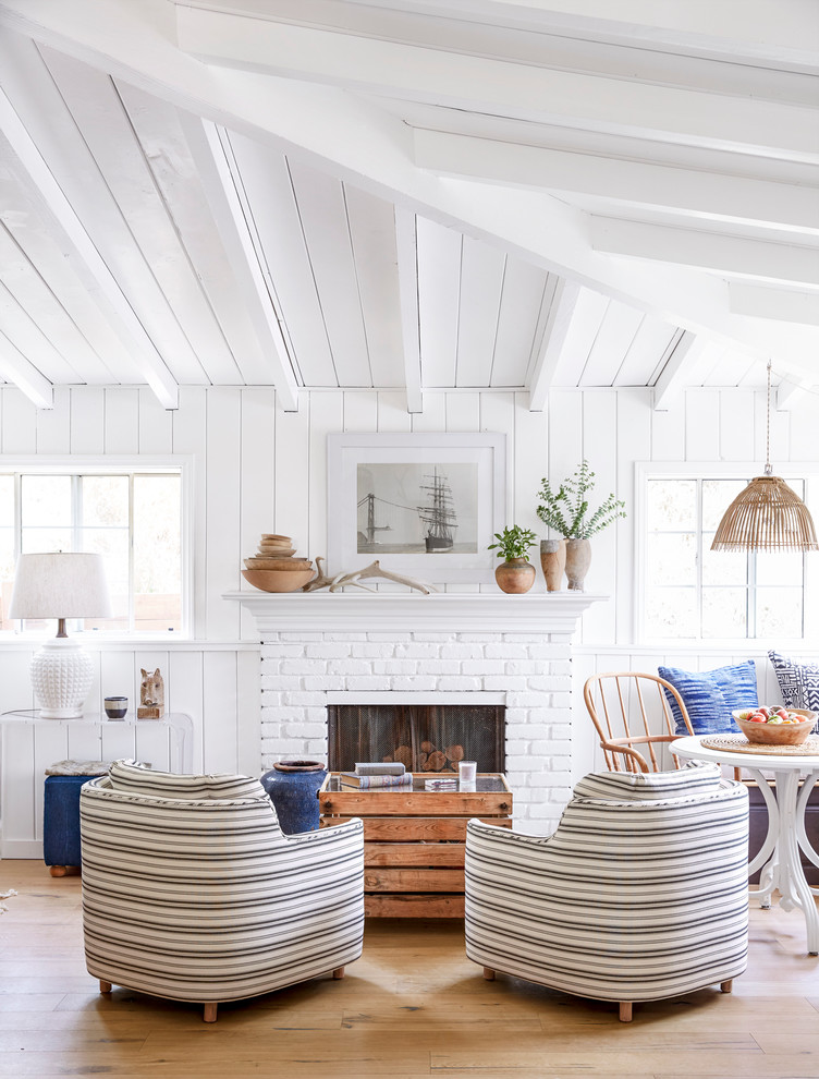 Inspiration for a small beach style open concept living room in Los Angeles with white walls, light hardwood floors, a standard fireplace, a brick fireplace surround and no tv.