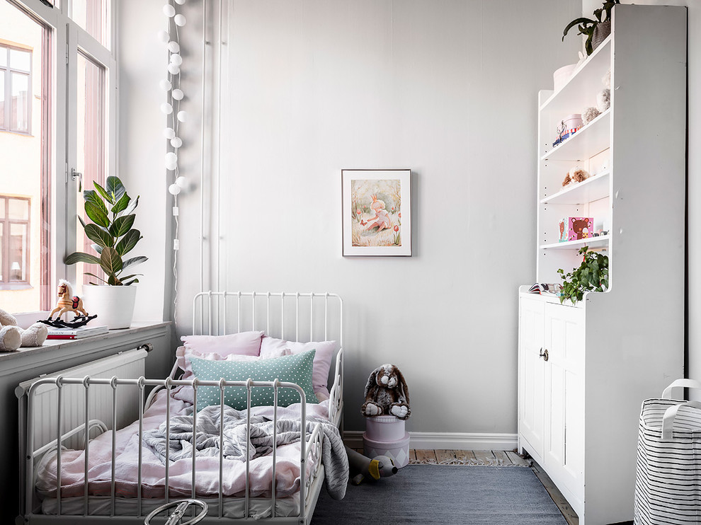 Small scandinavian kids' room in Gothenburg with white walls, medium hardwood floors and brown floor for girls.
