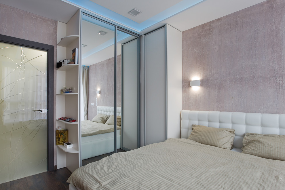 This is an example of a small contemporary master bedroom in Saint Petersburg with pink walls, laminate floors and brown floor.