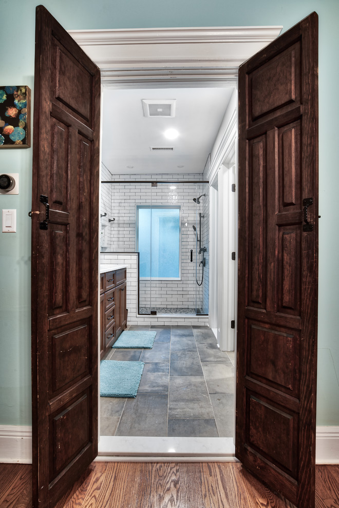 Photo of a large country master bathroom in New York with medium wood cabinets, an alcove shower, white tile, a drop-in sink, granite benchtops, a hinged shower door, white benchtops, grey walls, ceramic floors, grey floor, subway tile and a two-piece toilet.