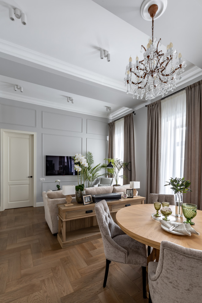 На фото: объединенная, серо-белая гостиная комната среднего размера в стиле неоклассика (современная классика) с серыми стенами, паркетным полом среднего тона, телевизором на стене, коричневым полом и балками на потолке