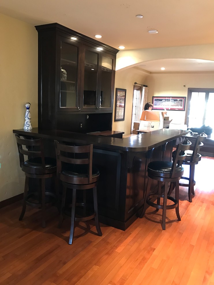 Design ideas for a large traditional galley seated home bar in Los Angeles with a drop-in sink, raised-panel cabinets, dark wood cabinets, quartz benchtops, brown splashback, timber splashback and medium hardwood floors.
