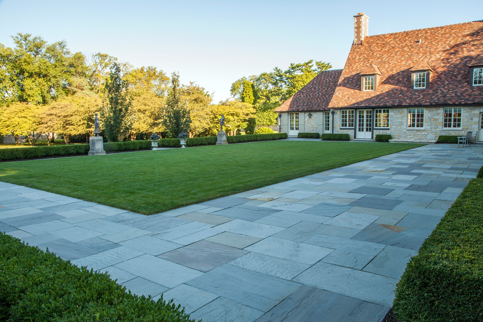 Photo of a large traditional partial sun formal garden for summer in Chicago with natural stone pavers.