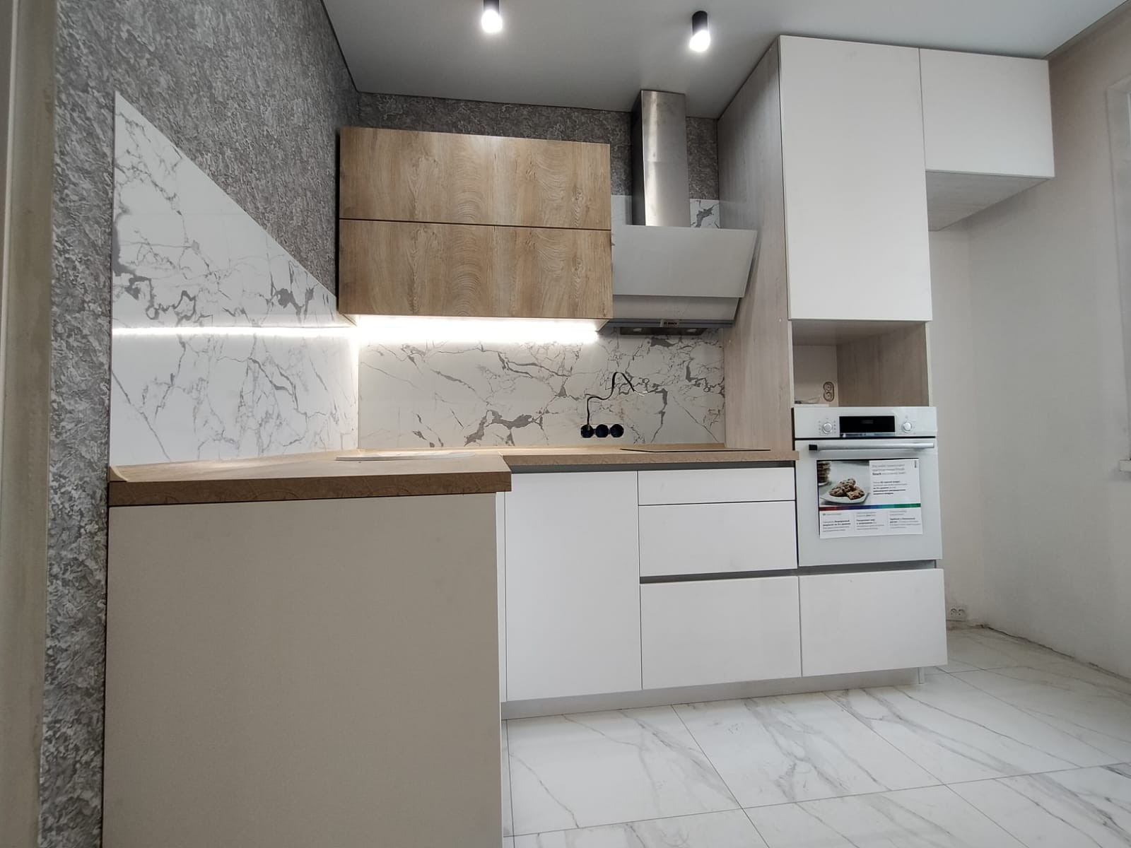 Светлая угловая белая кухня с горизонтальными верхними шкафами