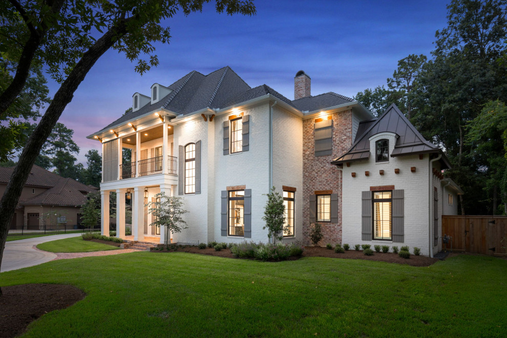 Large and white two floor brick detached house in Houston with a hip roof, a mixed material roof and a grey roof.