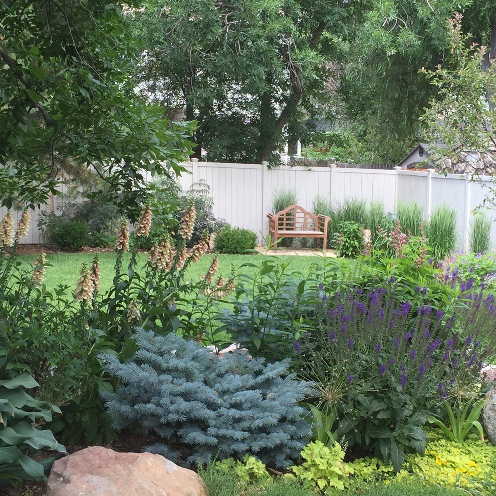 Photo of a mid-sized contemporary backyard partial sun xeriscape for summer in Denver with a retaining wall and concrete pavers.