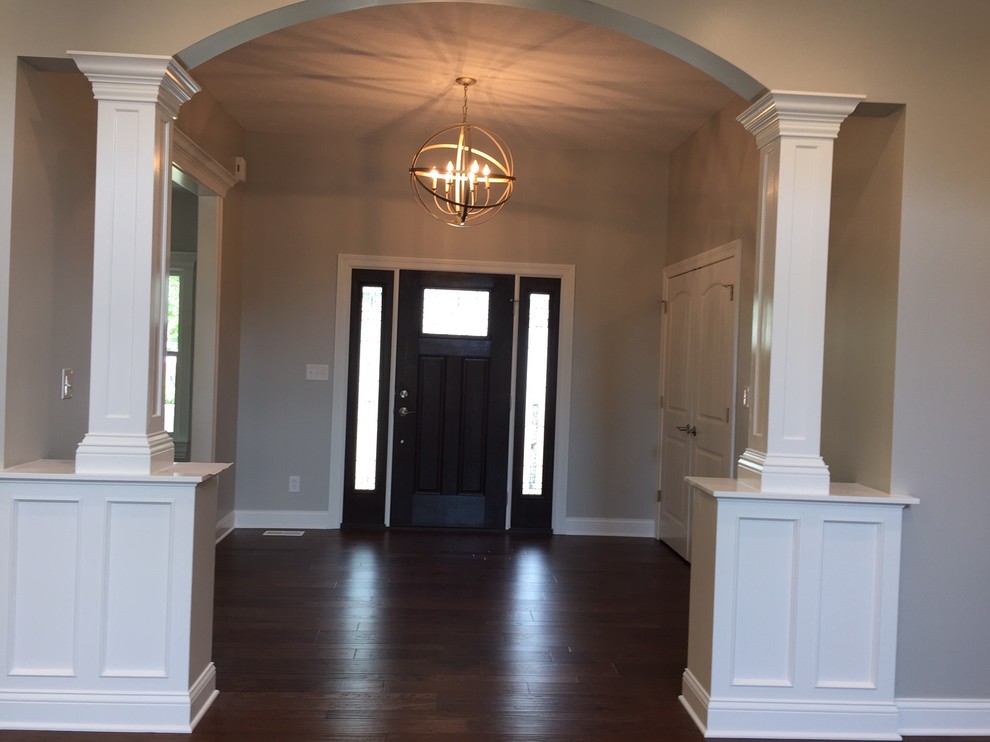 Example of a transitional dark wood floor foyer design with beige walls and a dark wood front door