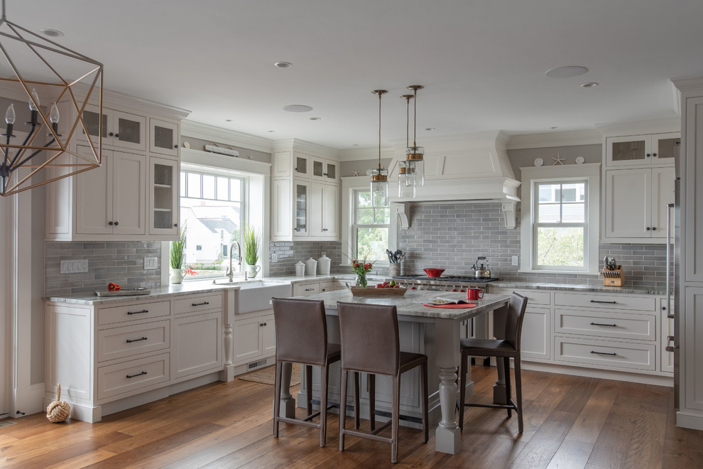 Inspiration for a large transitional u-shaped kitchen in Boston with a farmhouse sink, beaded inset cabinets, white cabinets, marble benchtops, grey splashback, subway tile splashback, stainless steel appliances, with island, grey benchtop, dark hardwood floors and brown floor.
