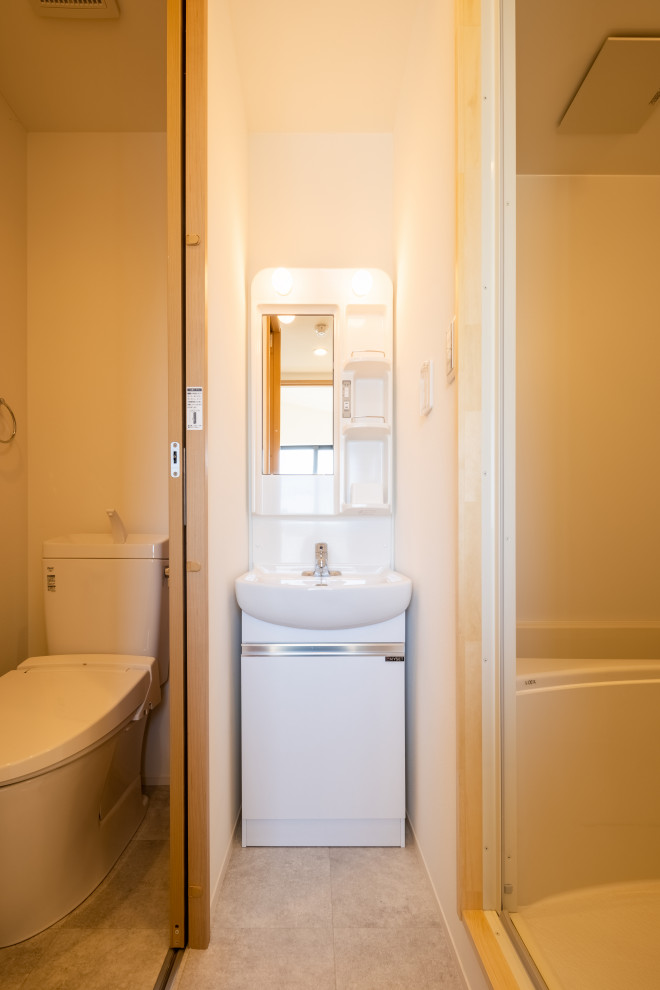 Idéer för små funkis vitt toaletter, med släta luckor, vita skåp, en toalettstol med hel cisternkåpa, vita väggar, vinylgolv och grått golv