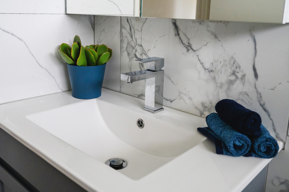 Photo of a modern bathroom in Melbourne with shaker cabinets, grey cabinets, a built-in bath, black and white tiles, porcelain tiles, white walls, porcelain flooring, solid surface worktops, grey floors, white worktops, a wall niche, a single sink and a freestanding vanity unit.