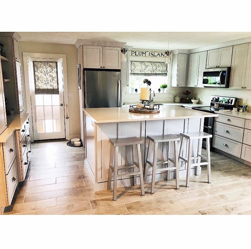 This is an example of a mid-sized beach style eat-in kitchen in Boston with an undermount sink, shaker cabinets, quartz benchtops, white splashback, shiplap splashback, stainless steel appliances, ceramic floors, with island, beige floor and white benchtop.