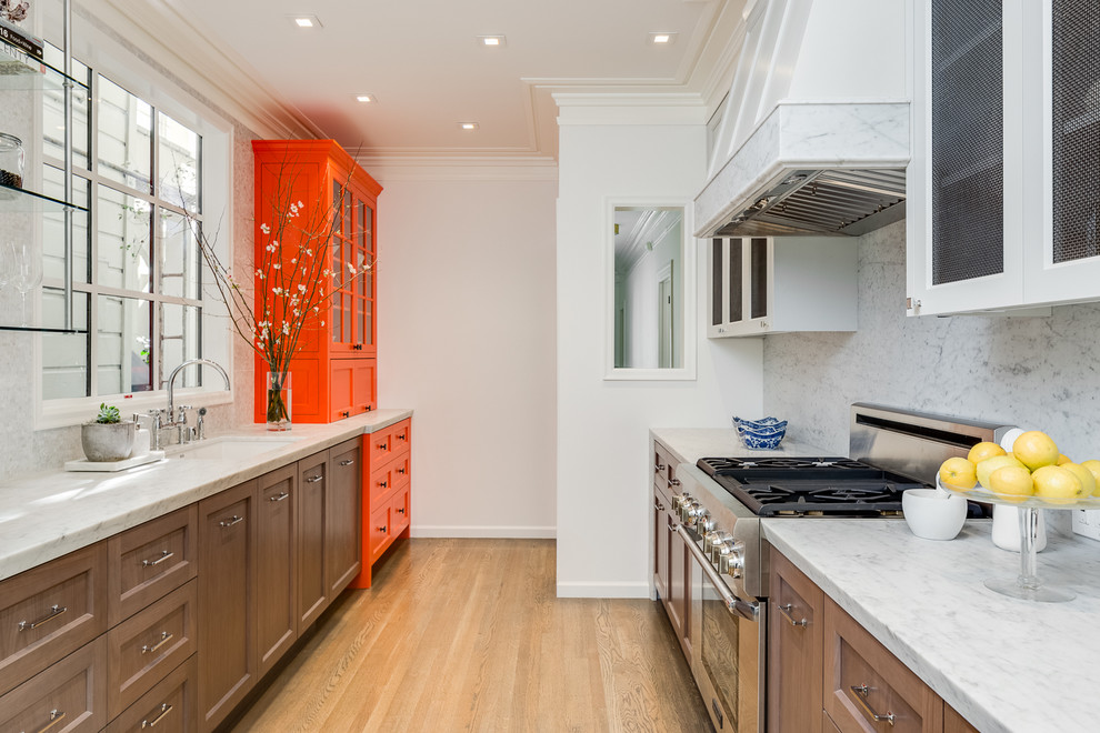 Photo of a traditional galley separate kitchen in San Francisco with recessed-panel cabinets, dark wood cabinets, white splashback, stone slab splashback and beige floor.