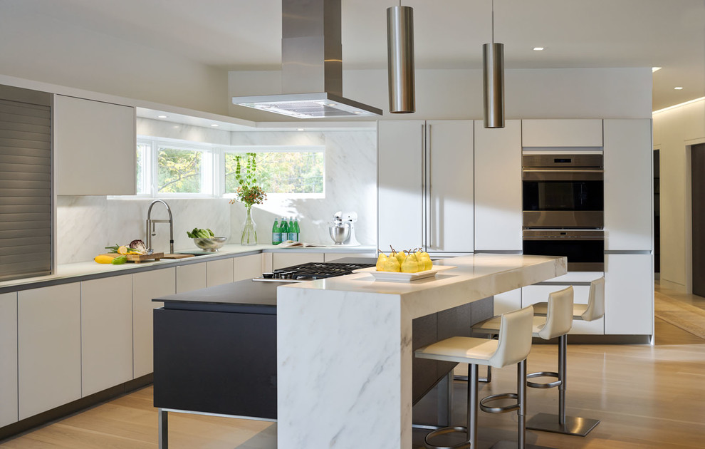 Inspiration for a contemporary l-shaped kitchen in Burlington with flat-panel cabinets, white cabinets, light hardwood floors, with island, white splashback and stone slab splashback.