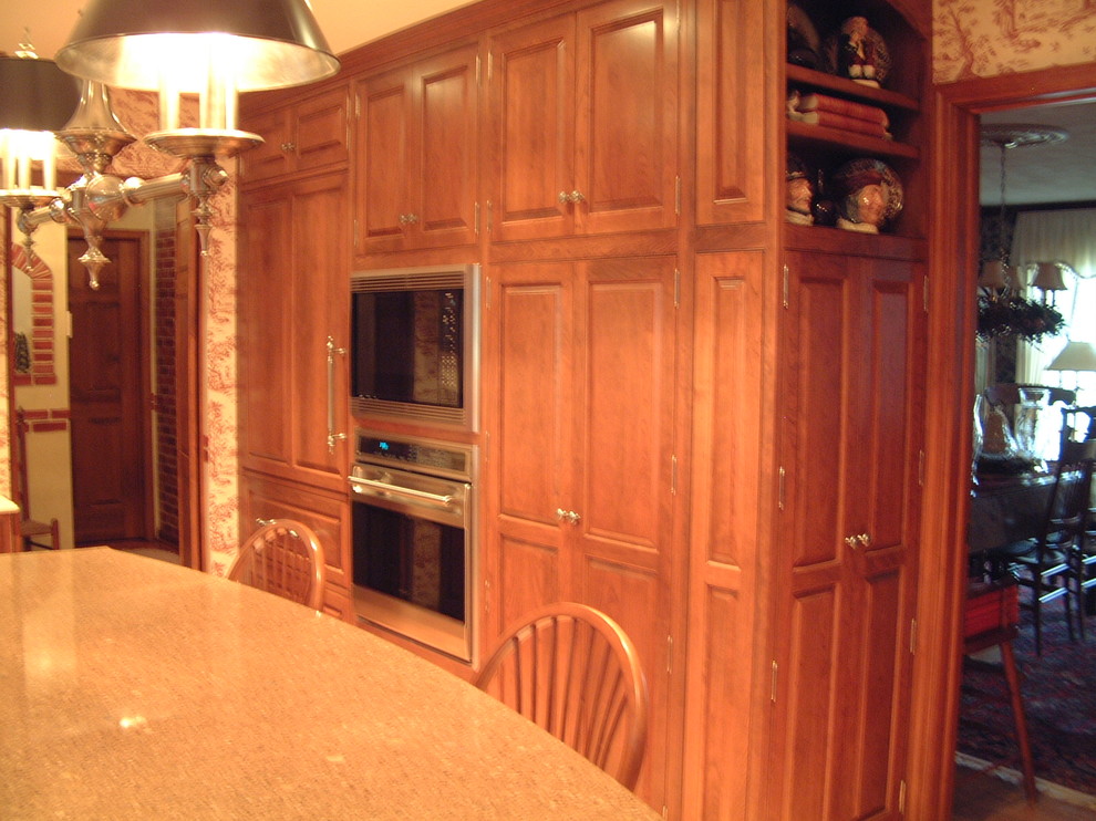 This is an example of a large traditional kitchen pantry in Chicago with a farmhouse sink, beaded inset cabinets, medium wood cabinets, beige splashback, stainless steel appliances, light hardwood floors and with island.
