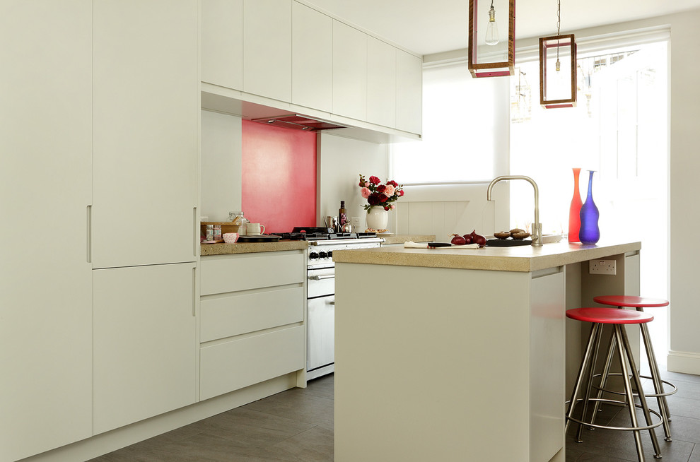 This is an example of a contemporary single-wall open plan kitchen in London with porcelain floors, with island, flat-panel cabinets, grey cabinets, concrete benchtops, pink splashback and panelled appliances.