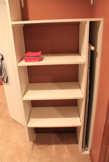 Huge minimalist gender-neutral carpeted walk-in closet photo with white cabinets