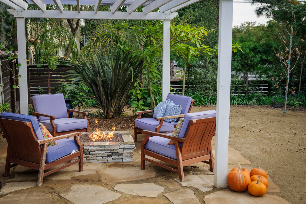 Photo of a mid-sized beach style backyard patio in Los Angeles with a fire feature, natural stone pavers and a pergola.