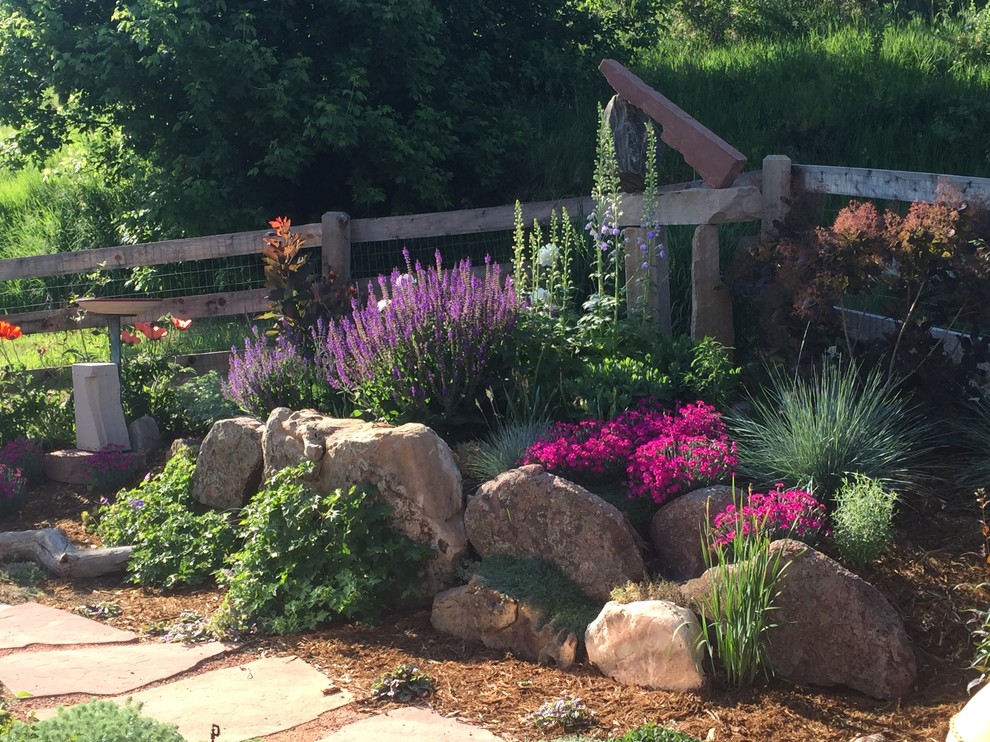 Design ideas for a large eclectic backyard full sun xeriscape in Denver with natural stone pavers and with rock feature.