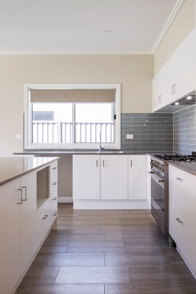 Inspiration for a mid-sized traditional l-shaped kitchen pantry in Newcastle - Maitland with a double-bowl sink, white cabinets, solid surface benchtops, grey splashback, subway tile splashback, stainless steel appliances, ceramic floors, with island, brown floor and brown benchtop.