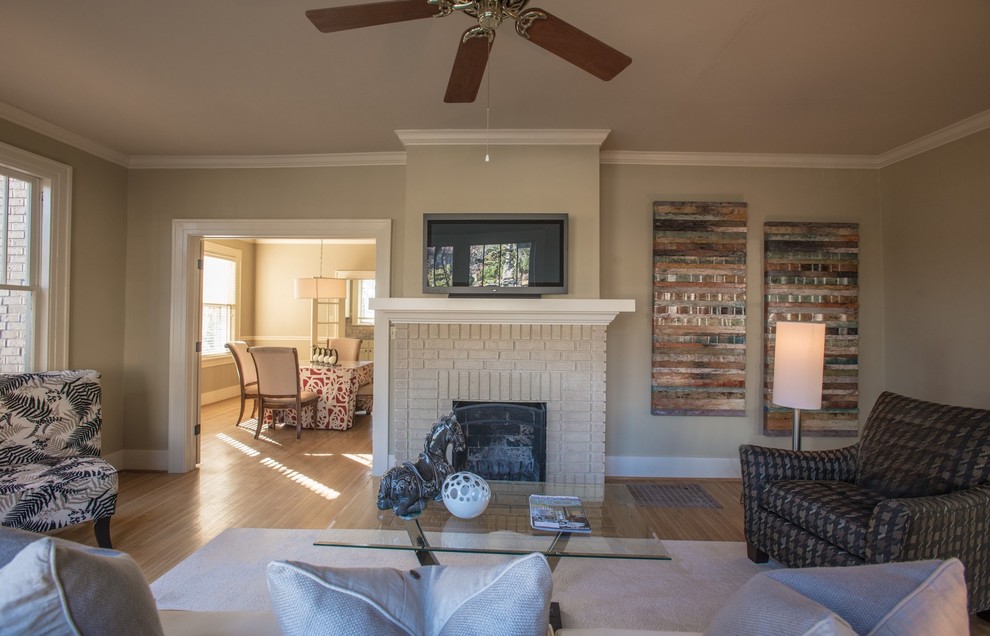 Mid-sized traditional enclosed family room in Little Rock with beige walls, light hardwood floors, a standard fireplace, a brick fireplace surround, a freestanding tv and brown floor.