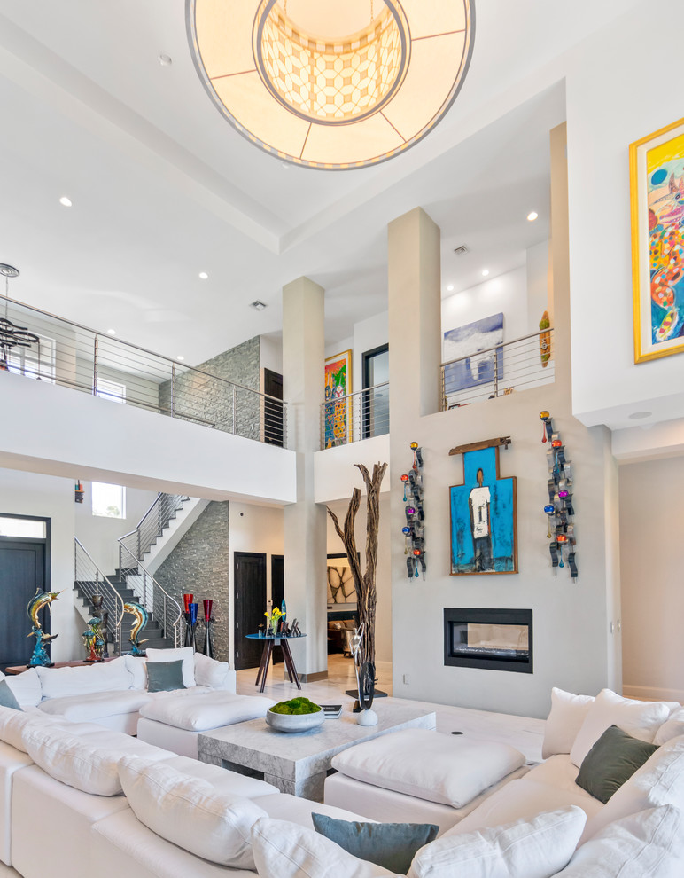 This is an example of a large transitional formal open concept living room in Miami with white walls, marble floors, a standard fireplace, a metal fireplace surround and white floor.