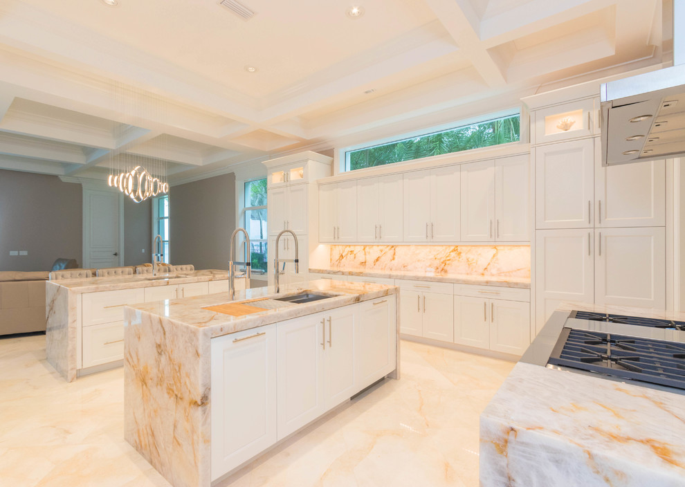 Huge transitional u-shaped marble floor and white floor open concept kitchen photo with an undermount sink, flat-panel cabinets, white cabinets, quartzite countertops, white backsplash, stone slab backsplash and two islands