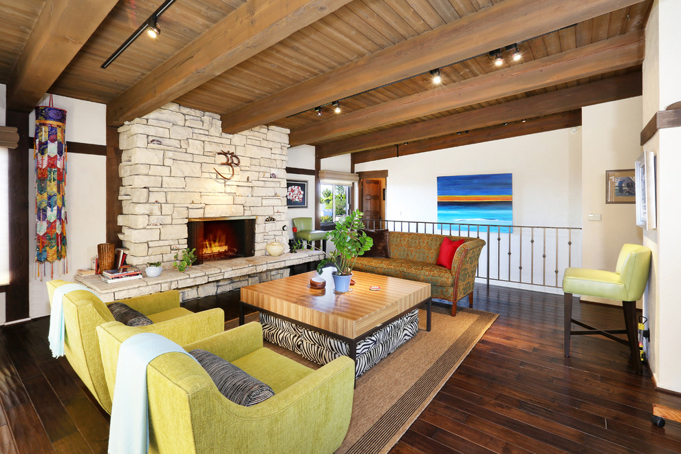 This is an example of a tropical living room in Orange County with dark hardwood floors, a standard fireplace and a stone fireplace surround.