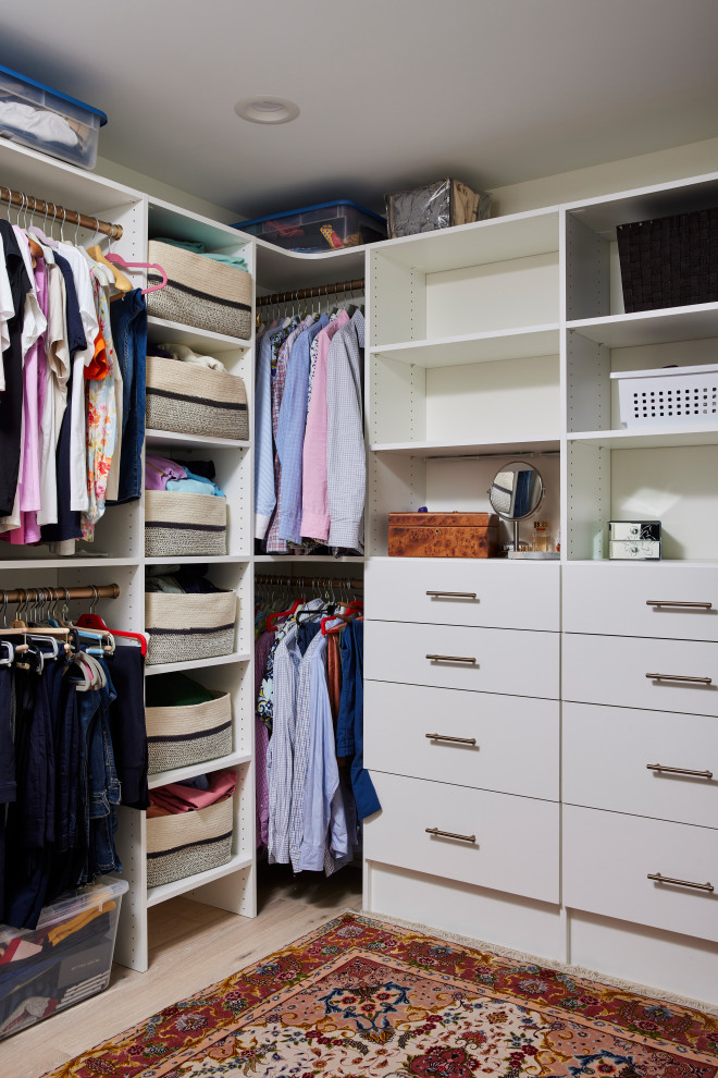 Example of a mid-sized trendy gender-neutral medium tone wood floor and beige floor walk-in closet design in Minneapolis with flat-panel cabinets and white cabinets