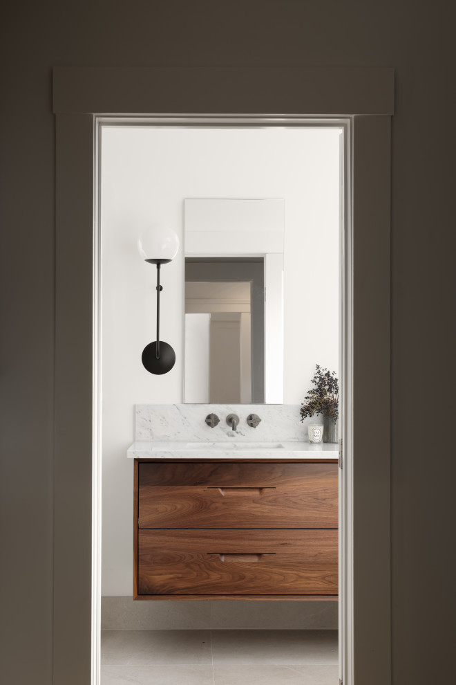 Exempel på ett mellanstort retro grå grått en-suite badrum, med släta luckor, skåp i mörkt trä, en toalettstol med hel cisternkåpa, vit kakel, marmorkakel, vita väggar, klinkergolv i porslin, ett undermonterad handfat, marmorbänkskiva, brunt golv och dusch med gångjärnsdörr
