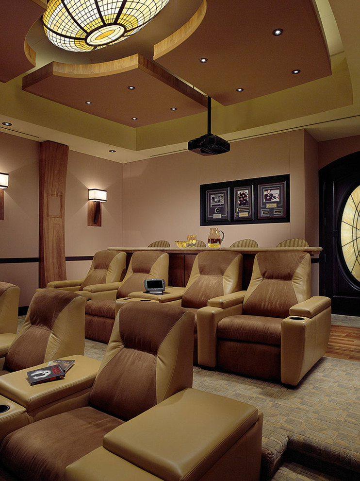 This is an example of a large mediterranean enclosed home theatre in Miami with beige walls, carpet and a projector screen.