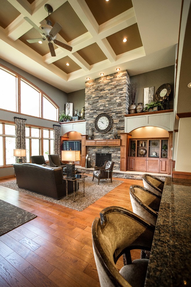 Inspiration for a large arts and crafts open concept family room in Other with grey walls, medium hardwood floors, a standard fireplace, a stone fireplace surround, a built-in media wall and brown floor.