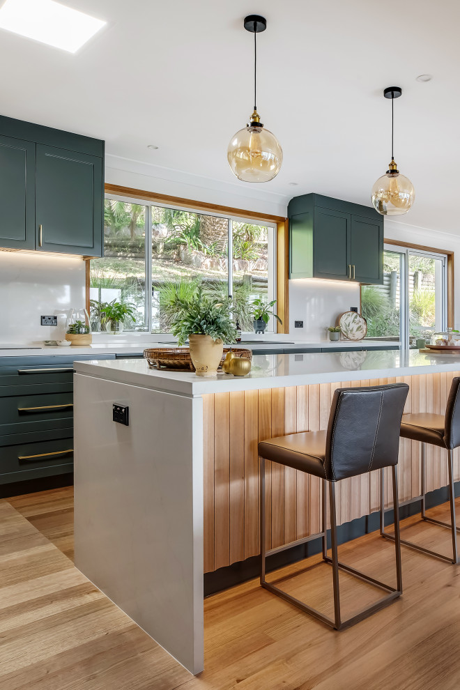 Eat-in kitchen - large transitional l-shaped medium tone wood floor and multicolored floor eat-in kitchen idea in Sydney with a drop-in sink, shaker cabinets, green cabinets, quartz countertops, white backsplash, quartz backsplash, black appliances, an island and white countertops