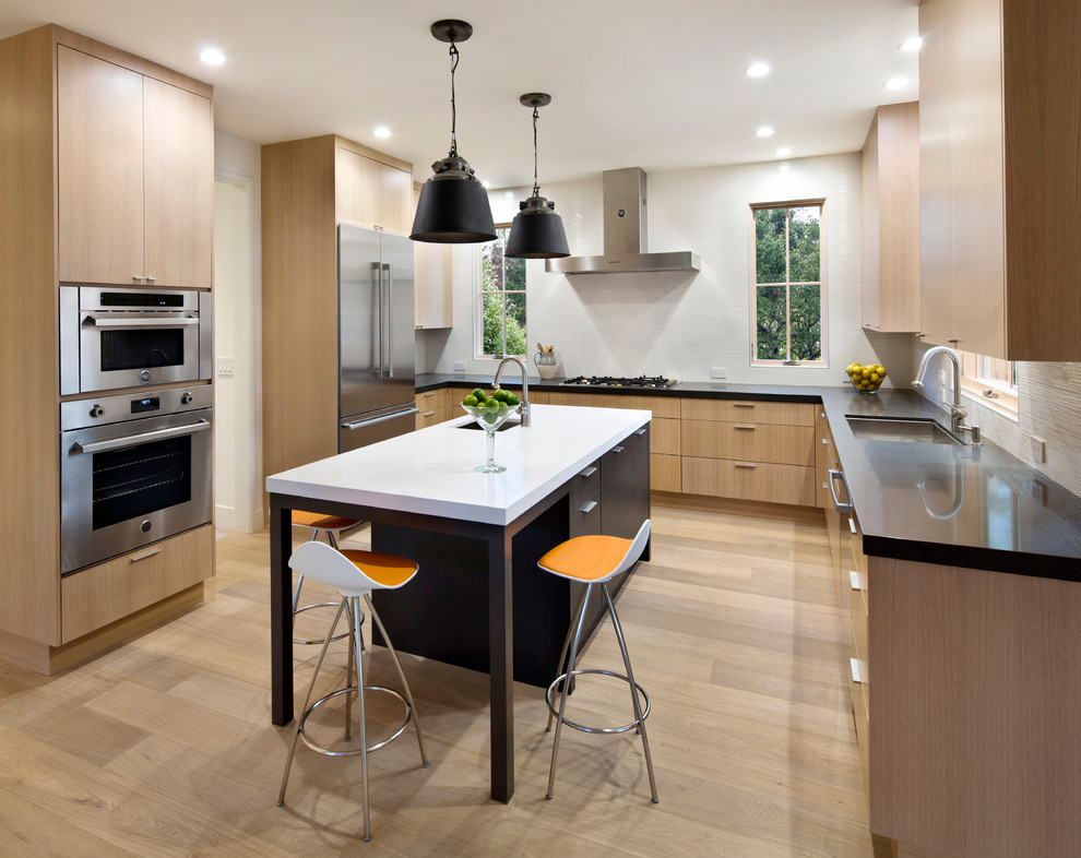 Design ideas for a mid-sized contemporary u-shaped kitchen in San Francisco with a single-bowl sink, quartz benchtops, stainless steel appliances, with island, flat-panel cabinets, light wood cabinets and light hardwood floors.
