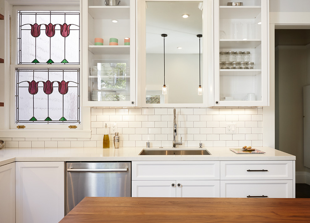 Photo of a mid-sized traditional l-shaped eat-in kitchen in San Francisco with a single-bowl sink, shaker cabinets, white cabinets, quartz benchtops, white splashback, subway tile splashback, stainless steel appliances, dark hardwood floors, with island and beige benchtop.