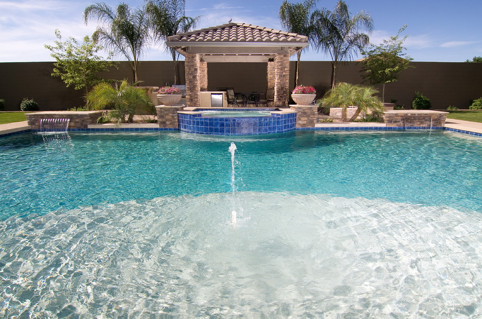Large mediterranean backyard custom-shaped pool in Phoenix with a pool house and natural stone pavers.