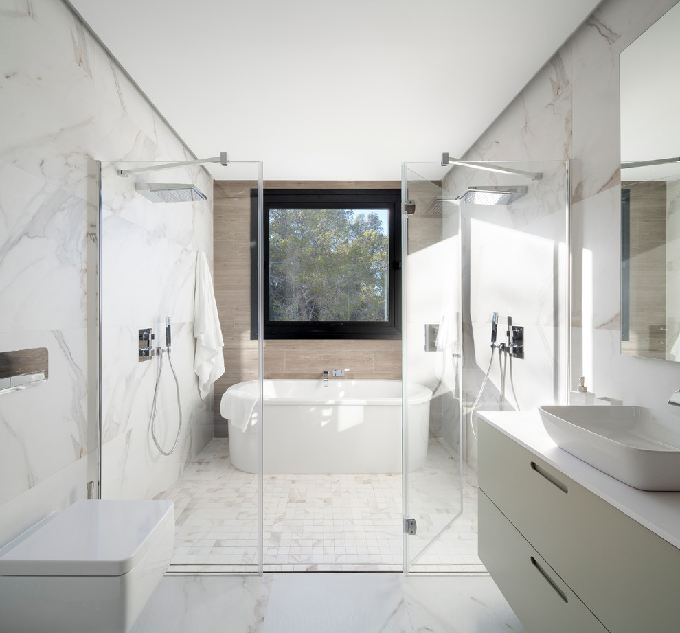 Photo of a large contemporary master bathroom in Other with flat-panel cabinets, white cabinets, a freestanding tub, a double shower, a wall-mount toilet, white walls, a vessel sink and a hinged shower door.