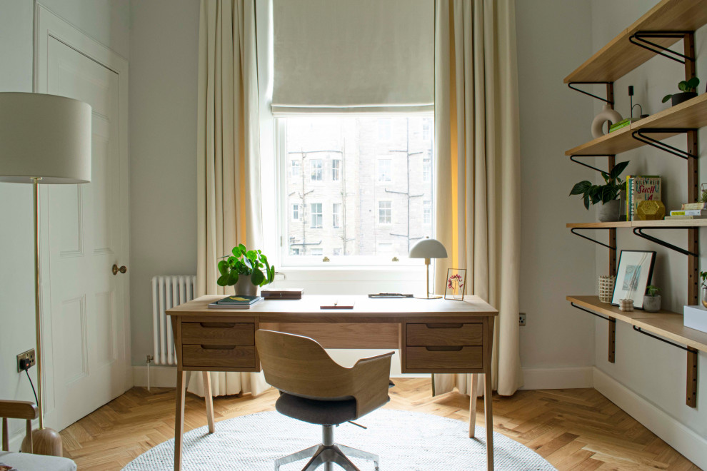Foto på ett mellanstort minimalistiskt hemmabibliotek, med grå väggar, mellanmörkt trägolv, ett fristående skrivbord och brunt golv