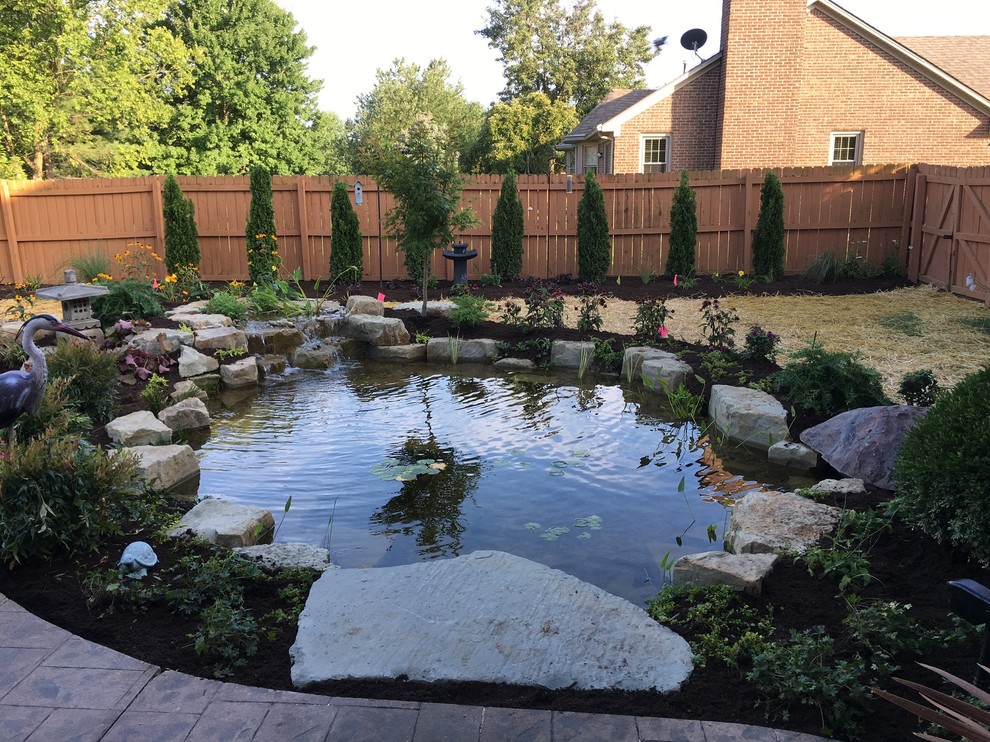 Photo of a large traditional backyard partial sun formal garden for summer in Other with with pond and natural stone pavers.