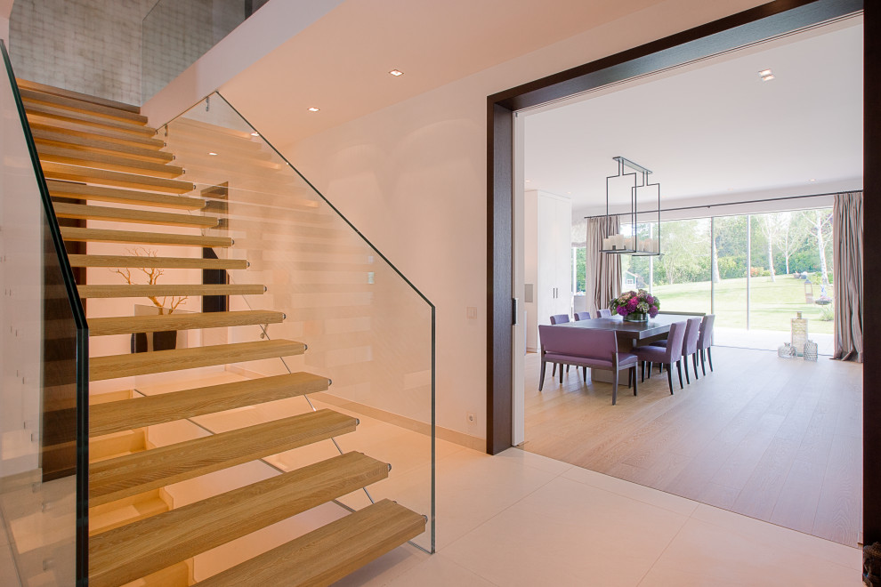 Photo of an expansive contemporary entryway in Other with white walls, limestone floors, a pivot front door, a brown front door and beige floor.