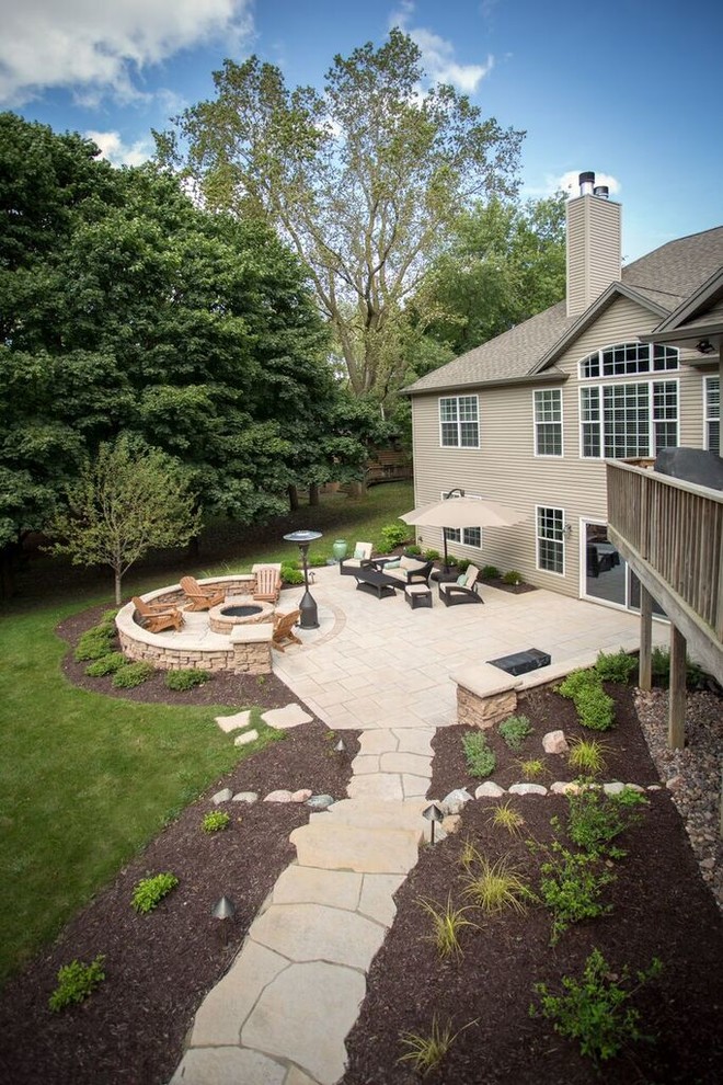 Inspiration for a large transitional backyard stone patio remodel in Chicago with a fire pit and no cover