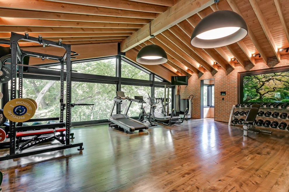Expansive arts and crafts home weight room in Toronto with red walls, dark hardwood floors and brown floor.