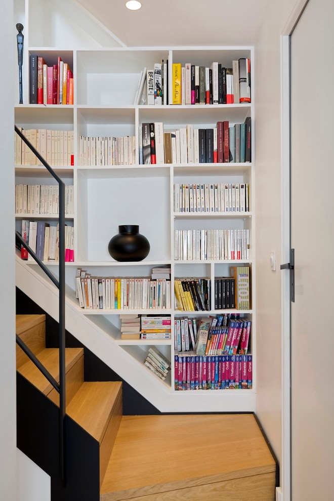 This is an example of a contemporary wood u-shaped staircase in Paris with wood risers and metal railing.