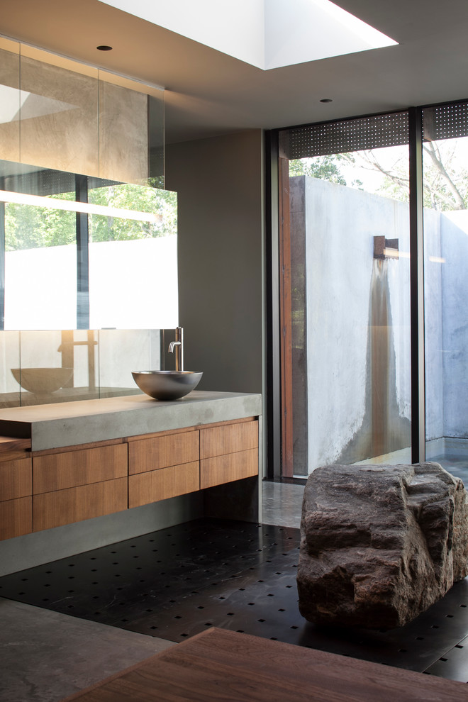 Photo of a contemporary bathroom in Kansas City with a vessel sink, flat-panel cabinets, medium wood cabinets, grey walls and grey benchtops.